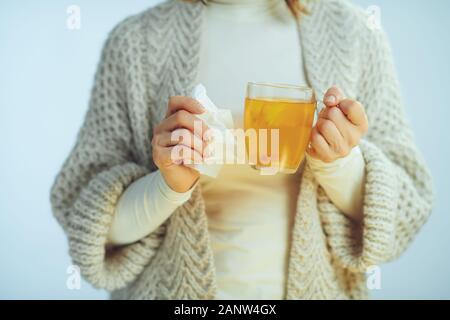 Gros plan sur moderne malade de 40 ans femme au foyer en rouleaux et du cou cardigan holding tasse de thé au gingembre, citron et miel et vinaigre isoler Banque D'Images