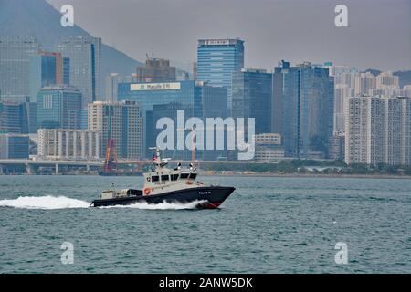 Un bateau de police voyage dans le port de Victoria en tant que smog enveloppe les gratte-ciel du centre-ville de Hong Kong. Banque D'Images