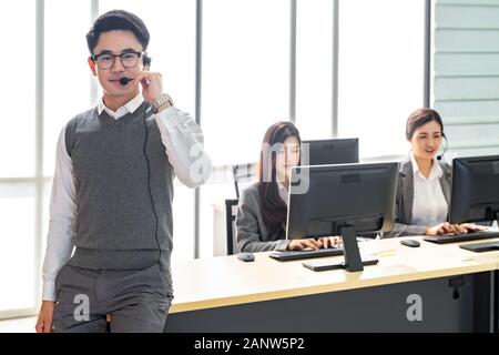 Portrait de jeune adulte friendly et la confiance avec l'homme de l'opérateur des casques et son équipe de travail dans un centre d'appels que le service client et technique sup Banque D'Images