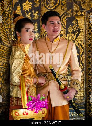 Jeune couple pose pour photo de mariage portant des costumes traditionnels, Wat Xien Thong temple, Luang Prabang, Laos Banque D'Images