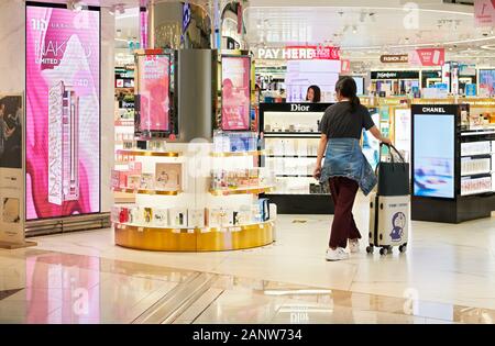 Hong Kong : Jeune femme entre dans une pièce lumineuse de beauté à l'intérieur de la zone de transit de l'Aéroport International de Hong Kong Banque D'Images