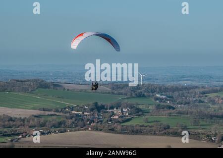 Firle, Lewes, East Sussex, Royaume-Uni..19 janvier 2020..Une belle journée ensoleillée avec du vent froid du Nord réunit pilotes de parapente à la belle South Downs. Cette photo montre plus de Firle Glynde pilote avec l'éolienne au-delà. David Burr/Alamy Live News. Banque D'Images