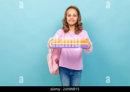 Une jeune fille d'école joyeuse avec des livres en blouse violette sourires Banque D'Images