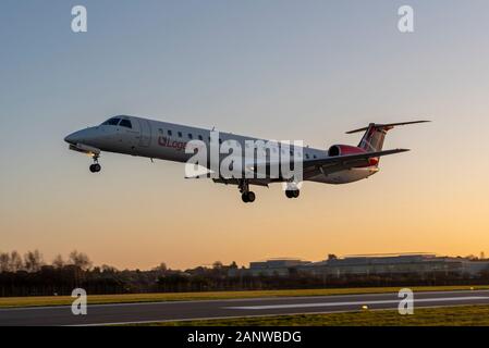 Loganair Embraer ERJ-145 avion jet G-SAJG atterrissage à l'aéroport London Southend, Essex, Royaume-Uni. Fin d'après-midi en hiver. Coucher De Soleil. Crépuscule. Orange chaud. Banque D'Images