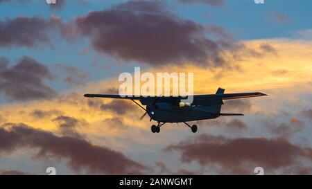 Tourné d'une silhouette d'avion privé, non identifiables en approche finale pour l'atterrissage au coucher du soleil. Banque D'Images