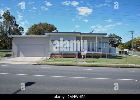 Maisons typiques d'après-guerre à Brisbane. Maison de banlieue bien entretenue, cour avant en herbe verte, panneau météo bas des années 50 1960 avec toit skillion, Cannon Hill Banque D'Images