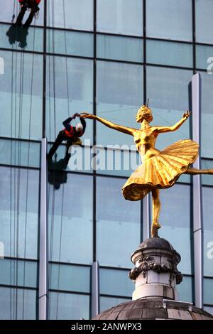 Statue de la ballerine russe Anna Pavlova sur le dessus du dôme de Victoria Palace Theatre et les travailleurs sur la façade de verre Building, Victoria, London, UK Banque D'Images