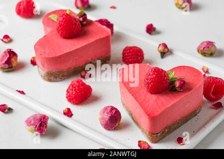 Gâteaux en forme de coeur végétalien premières ou de crème glacée avec des framboises fraîches, de menthe et de fleurs séchées. Valentines Day dessert. Une alimentation saine concept. close up Banque D'Images