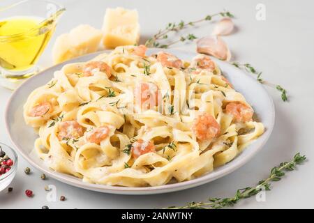 Les pâtes italiennes ou tagliatelle fettuccine dans une sauce crémeuse aux crevettes dans une assiette sur la table en marbre blanc. close up Banque D'Images