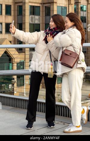 Millennium Bridge London People deux jeunes femmes asiatiques souriant et posant pour la photo et prenant selfie sur le Millennium Bridge à Londres, Royaume-Uni Banque D'Images
