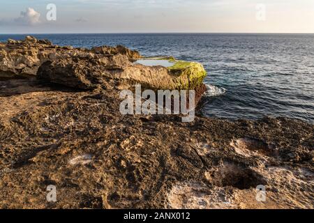 Rivage rocheux à Devil's larme sur île de Nusa Lembongan, à Bali, Indonésie. Côte Rocheuse avec cuvette en premier plan. L'océan, littoral, ciel & nuages. Banque D'Images