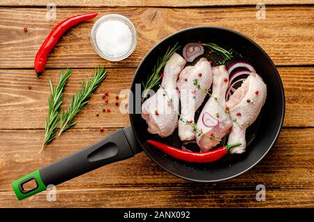 Cuisses de poulet cru mariné ou pilons avec épices et fines herbes dans une poêle pour la cuisson. Concept cuisine méditerranéenne. Vue d'en haut Banque D'Images
