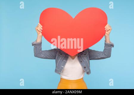 Femme anonyme en tenue décontractée se cachant derrière immense cœur rouge, concept de l'amour secret amour, amant inconnu et l'affaire, sur la saint Valentin romantique d Banque D'Images