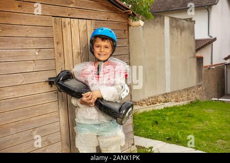 Petit enfant kid avec hoverboard et mère surprotectrice garder un garçon dans l'enveloppe de bulle sur le point d'aller à cheval très sûr Banque D'Images