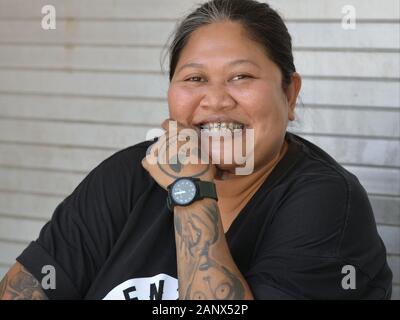 Les femmes potelées tatoueur balinais avec appareil dentaire sourire pour la caméra et montre son avant-bras des tatouages. Banque D'Images