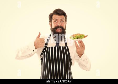La malbouffe. De délicieux croissants. Homme garçon barbu tablier porter porter la plaque avec de la nourriture. Cafe concept. Guy servant un croissant fourré avec de la laitue et les légumes frais. Alimentation saine. Les Calories et les régimes amaigrissants. Banque D'Images