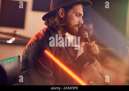 Side view portrait of handsome barbu chanter au micro pendant les concerts de musique contemporaine avec bande en studio, copy space Banque D'Images