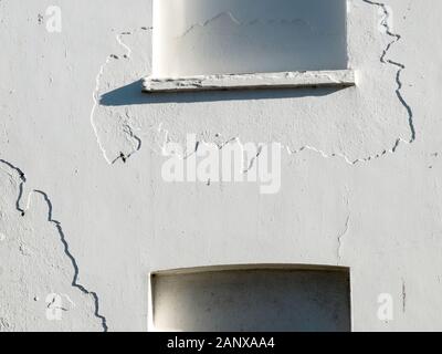 Plâtre des détails de mur blanc fissuré entourent des fenêtres bloquées sur une maison abandonnée à Broadstairs, Kent, Royaume-Uni Banque D'Images