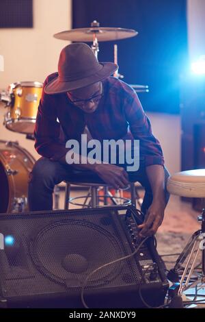 Portrait de musicien africain contemporain création d'ampli de guitare au cours de contrôle sonore tout en se préparant pour le concert ou répétition avec band en arrière-plan Banque D'Images
