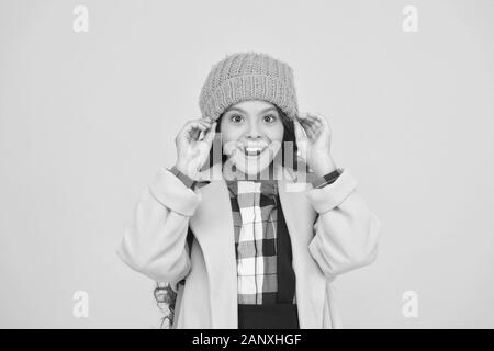 Bonnet hiver accessoire. Des cheveux longs de fille fond jaune. Saison froide concept. Accessoire de mode d'hiver. Petit enfant portant chapeau chaud. Choisissez entre plus mignonne et la plus branchée. Kid girl porter chapeau tricoté. Banque D'Images