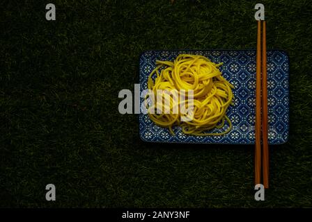 Nouilles Soba dans une plaque japonaise sur fond d'herbe verte, vue du dessus, copiez l'espace. Banque D'Images