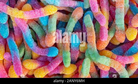 Pile de vers de gummy sucrées au néon ou de crawers aigre crawy arrière-plan. Gros plan de friandises sucrées et aigres colorées et savoureuses enrobées de cristaux de sucre Banque D'Images