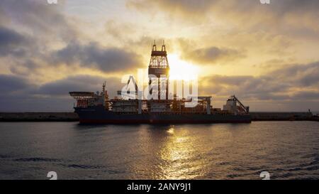 Lever du soleil au-dessus d'un navire de forage amarré nommé Deepwater Mykonos naviguant sous le drapeau du Liberia et géré par Transocean, Puerto de las Palmas, Espagne Banque D'Images