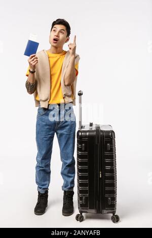Long Shot verticale modèle masculin asiatique 20s en jaune t-shirt, jeans, lever l'index geste eureka, ont une grande idée, où le voyage Banque D'Images