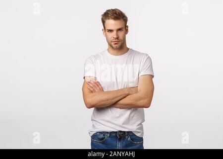 Confiant, mature blonde athlétique gars en t-shirt blanc, les mains sur la poitrine et sourit avec assurance, expression déterminée, impliqués Banque D'Images