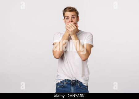 Choquée concernait les jeunes garçon blond découvert dirty secret, des commérages, bouche fermée, appuyez sur palm pour lèvres et regarder sans voix, abasourdi assiste à l'appareil photo Banque D'Images