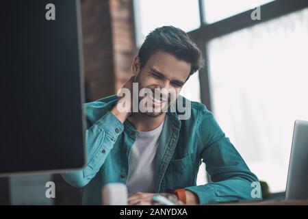 Malheureux jeune homme la sensation de douleur dans son cou Banque D'Images