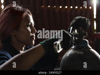 Apprenti ingénieur industriel féminin, inspection et entretien des bouteilles de gaz comprimé dans l'usine de production - stagiaire stagiaire stagiaire, apprentissage des compétences professionnelles pendant l'expérience de travail Banque D'Images