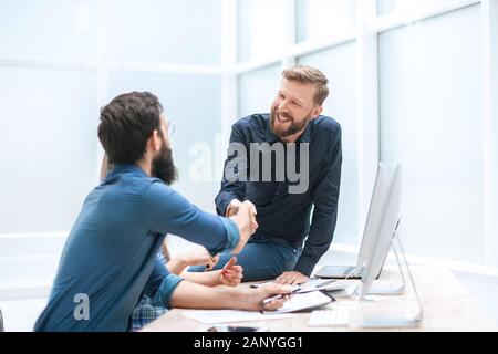 Smiling colleagues shaking hands près du bureau. Banque D'Images