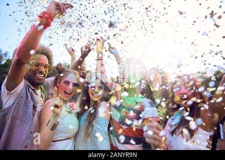 Les amis de célébrer holi festival sous pluie de confettis Banque D'Images