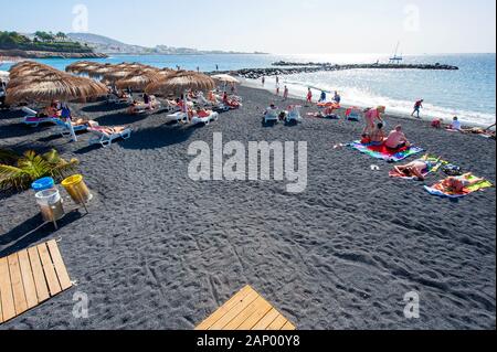 Île des Canaries Tenerife, Espagne - 27 déc, 2019 : les touristes sont de détente et de jouer sur une plage appelée Playa El Beril sur Ténérife. Une plage de gravier noir. Banque D'Images