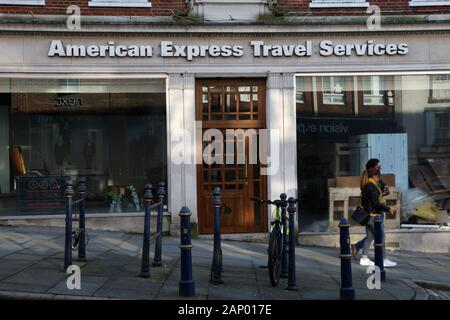 Deux piétons à l'arrêt devant une vitrine des services de voyage American Express à Guildford high street, Surrey, UK, Janvier 2020 Banque D'Images