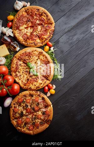 Servi frais, trois différentes pizzas placé parmi des ingrédients savoureux. Vue d'en haut Banque D'Images