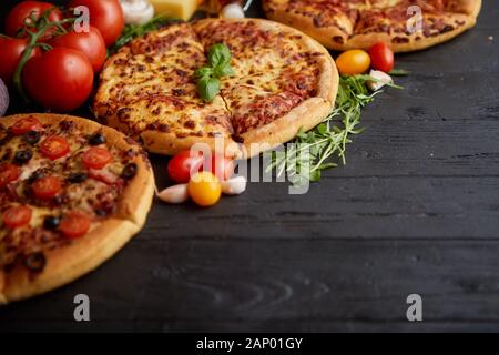 Servi frais, trois différentes pizzas placé parmi des ingrédients savoureux. Vue d'en haut Banque D'Images