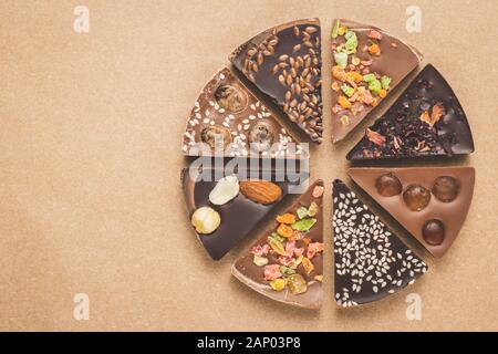 Morceaux de chocolat noir et lait aux épices sur fond brun. Tranches de chocolats sur le papier kraft, vue d'en haut. Carte de souhaits avec copie espace. Homem Banque D'Images