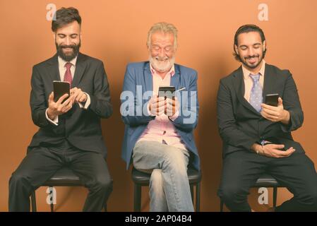 Trois hommes barbus multi ethnic ensemble contre fond brun Banque D'Images