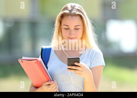Vue avant portrait d'étudiant sérieux girl listening to music portant des écouteurs-checking mobile phone Banque D'Images