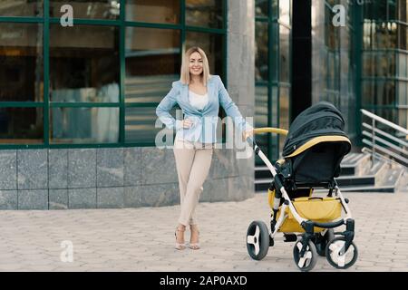 Portrait d'une femme d'affaires en costume bleu avec bébé près de l'immeuble de bureaux Banque D'Images