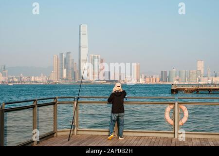 Fisher man avec la canne à pêche sur la côte avec des toits de HongKong Banque D'Images