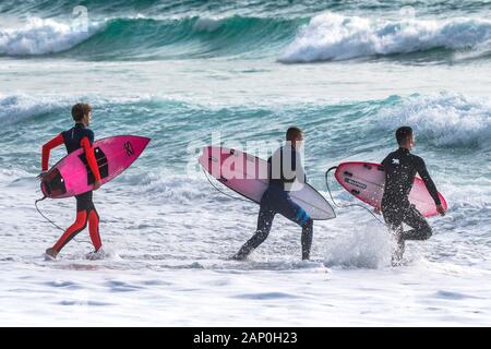 Leurs Surfers carrying surfboards et tournant vers la mer, dans la région de Fistral Newquay en Cornouailles. Banque D'Images