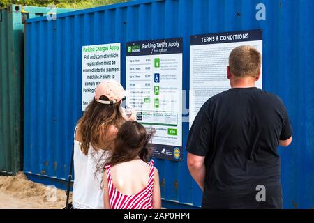 Une famille de vacanciers à la recherche au les frais de stationnement au Parking dans Fistral Newquay en Cornouailles. Banque D'Images