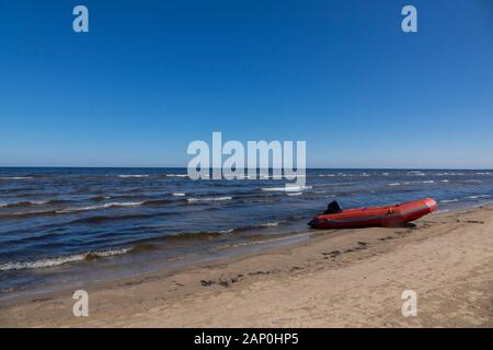 Bateau en caoutchouc sur une plage de sable sur un fond de ciel bleu. Banque D'Images