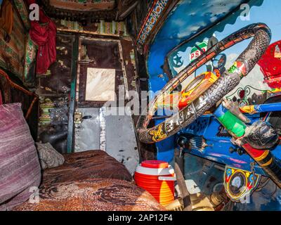 Vue à l'intérieur de la cabine d'un camion coloré et peint, conduisant sur les routes poussiéreuses de l'autoroute Karakorum Banque D'Images