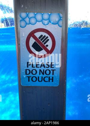 Un autocollant d'avertissement sur un post qui dit merci de ne pas toucher à un réservoir d'aquarium. Banque D'Images