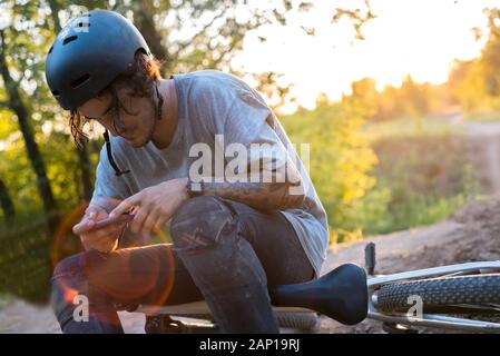 Les gens, sports, style de vie actif et de la technologie moderne. Une photo de cycliste sur vélo d'appoint à l'aide de navigateur sur téléphone intelligent, l'exploration de la carte et s Banque D'Images