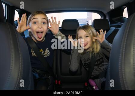 Deux enfants à l'arrière d'une voiture font des visages bizarres Banque D'Images